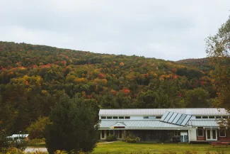 A wide shot of the main building with fall foliage hillsides in the background.