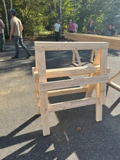 Two sawhorses stacked on top of each other on blacktop.