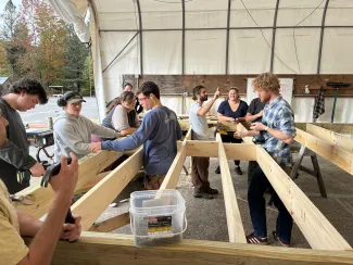 2026 Semester students gather around their floor deck in the outdoor hangar, working to finish up the framing.