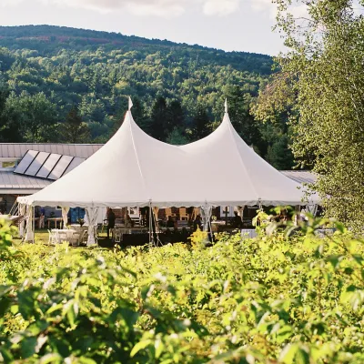A wide shot of a white celebration tent on the lawn in front of the main building.