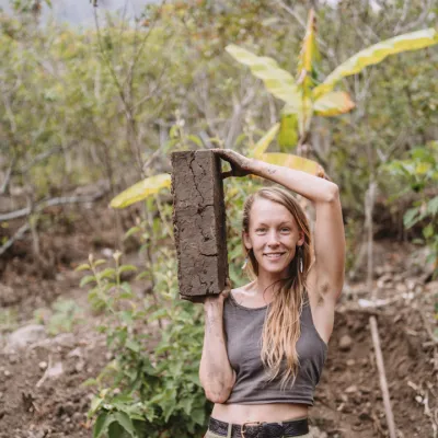 Woman holds up a brick of clay