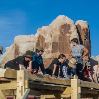 Students participate in a timber frame raising in the desert, with striking bluff formations in the background.
