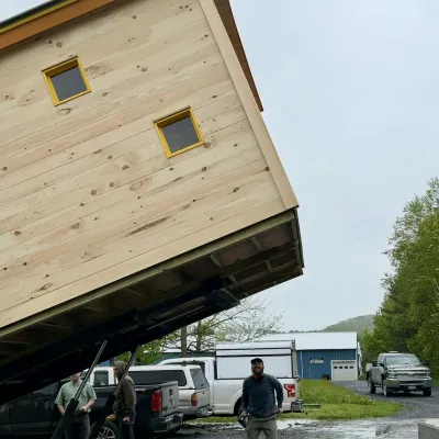 A bunkhouse building gets lifted onto a trailer.