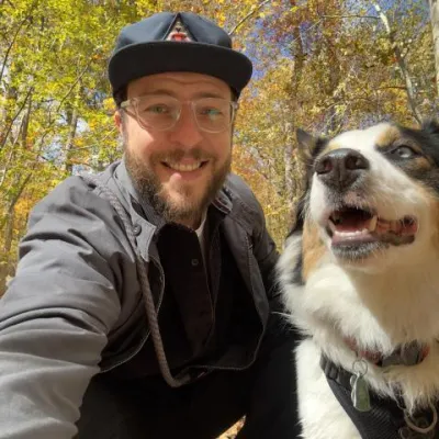 Chris smiles at the camera with his dog, Aspen