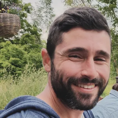 A man with dark hair and a beard smiles at the camera.