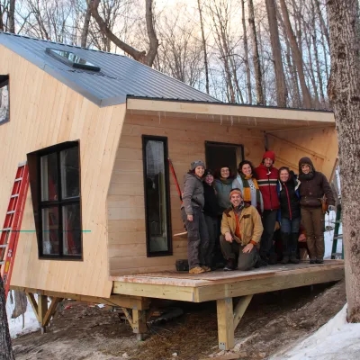 Small, newly built ADU Cabin in the woods, with a class of young builders on the deck.