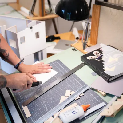 Shot of a student's drafting table with sketches and a model in progress.