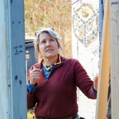 Lizabeth is wearing a red sweater and looking up at a framed structure.