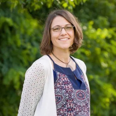 Woman with brown hair and glasses smiles at the camera