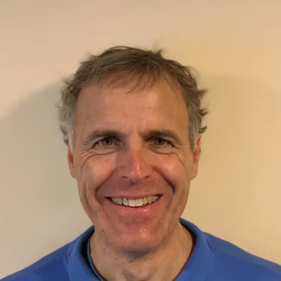 Middle aged man with a 5:00 shadow smiles big.