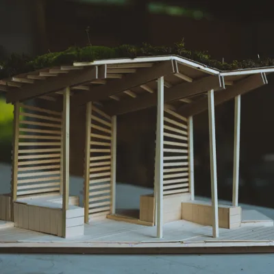 A wooden model of a bus stop structure featuring benches and wood slates designed by students in 2019.