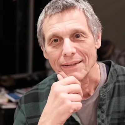 Stephen smiles at the camera, resting their head on their chin. 