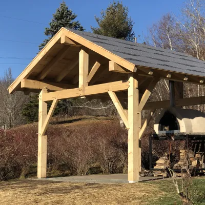 A timber frame over a pizza oven with blue sky in the background.