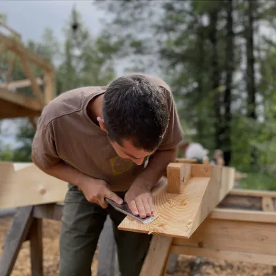 A student uses a chisel to cut the end of a timber.