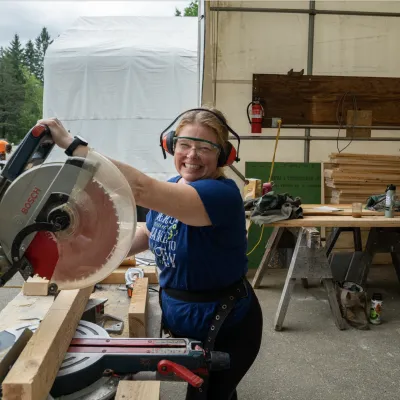 A student at a chop saw station smiles at the camera.