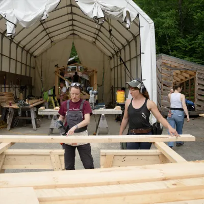 Two students figure out measurements on a piece of lumber.