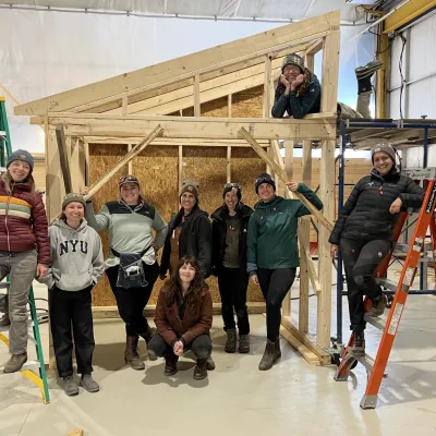 A group of students poses in front of their shed project.