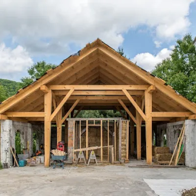 Wide shot of the Arches, an open timber frame pavilion over a concrete base. There is a wall under construction in the Arches.