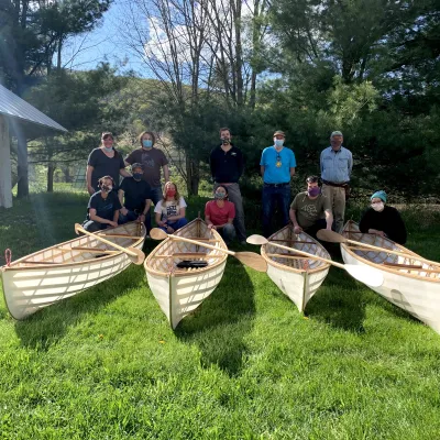A group of students and instructors with their completed boats at the end of class. 