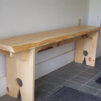 A shaker bench in the yestermorrow entryway with detailed cutout legs.