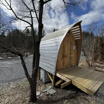 A composting toilet structure built by students in 2024 featuring a gothic arch style roof.