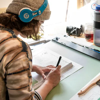 A student working on a drawing at a drafting table.