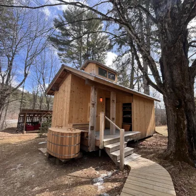 A sauna built to resemble a Sugar Shack with a cold plunge barrel near the entrance.