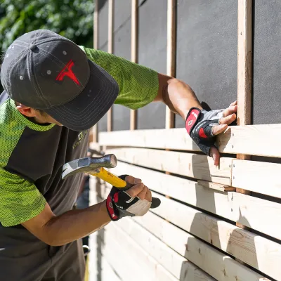 A student hammering a board onto a wall.