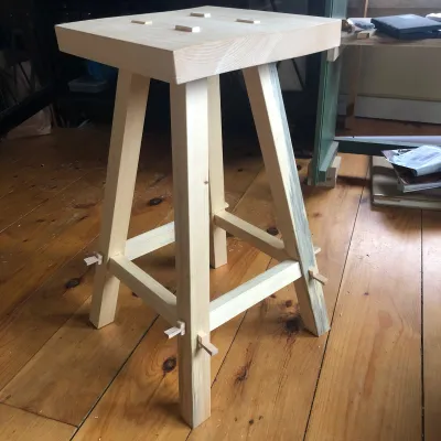 A simple wooden stool showing casing unique joinery in the legs and seat.