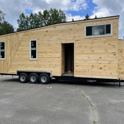 A tiny house on wheels with pine board siding. 