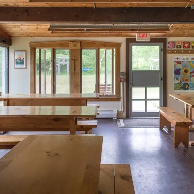 Reverse view of the yestermorrow kitchen, with tables in the foreground, looking outwards towards the lawn behind.