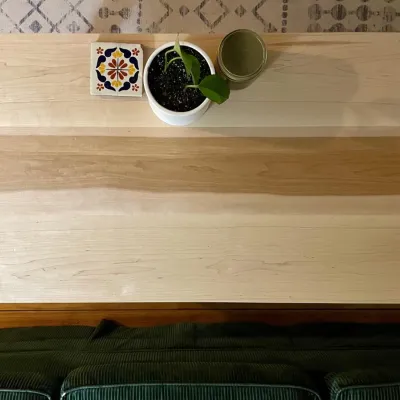 Photo of a maple coffee table from above with a plant and coaster