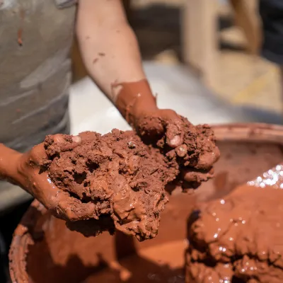 Detail shot of hands mixing straw and clay