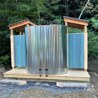 An outdoor shower structure featuring two stalls on either side and a curved metal wall in the middle.