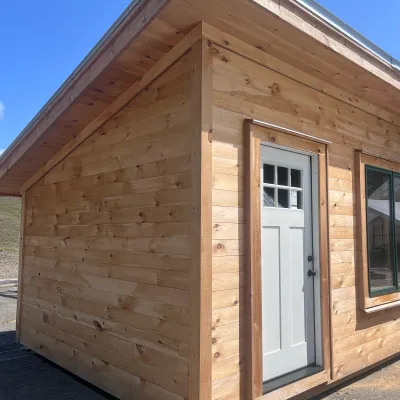 The exterior of a simple shed roof cabin with pine shiplap siding.