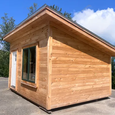The exterior of a simple shed roof cabin with pine shiplap siding.