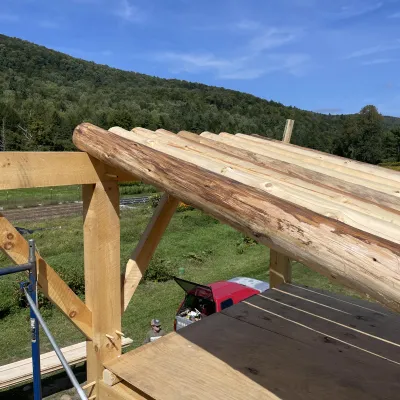 Round pole timbers resting on top of a timber frame structure as part of an installation. 