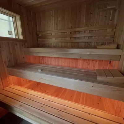 The interior or a sauna with 3 tiers of benches and under bench lighting. 