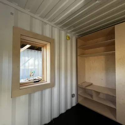 Interior of a 40' shipping container home focused on a custom built in wardrobe. 