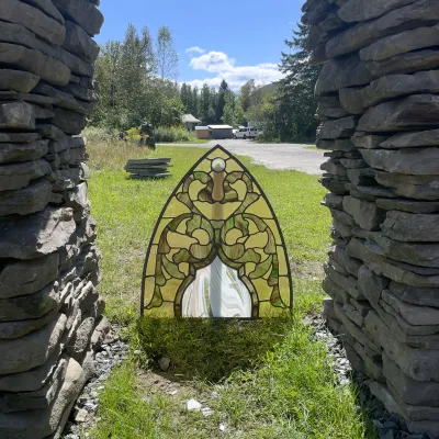 A stained glass panel in an arch shape is pictured outside.