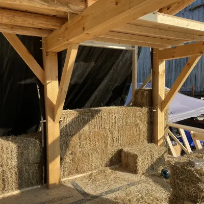 Strawbales stacked between a 2 timber framed bents to create a solid wall. 