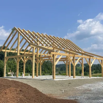 A completed timber frame stands against blue sky.