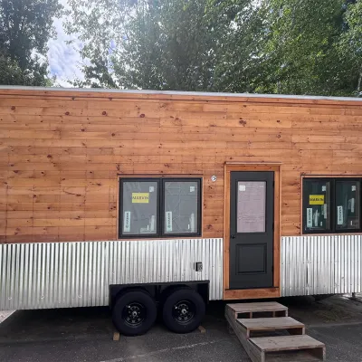 A tiny house on wheels with pine board siding.
