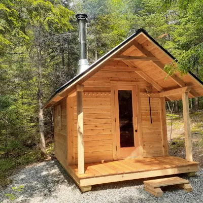 A wooden sauna with a gable roof in the forest. 