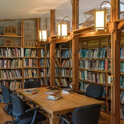 Photo of the yestermorow library, with shelves of books surrounding a central table with six chairs. 
