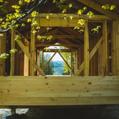 Wide shot of a framed building looking through the long way. There are branches with leaves in the foreground.