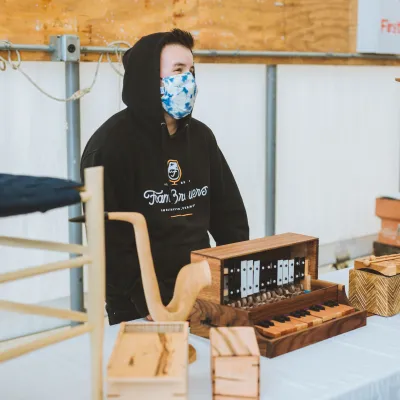 A student smiles behind their table of woodworking projects